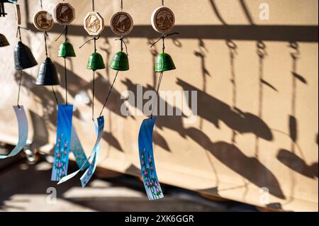 Une rangée de carillons de vent colorés suspendus à la lumière du soleil, projetant des ombres complexes sur un mur. Les carillons créent un motif visuellement agréable avec leur v Banque D'Images