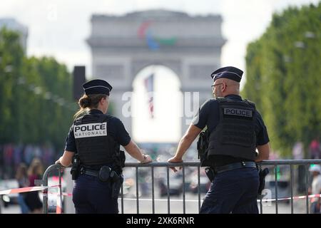 Paris, France. 21 juillet 2024. Avant les Jeux Olympiques d’été, Olympia Paris 2024, deux policiers se tiennent derrière une barrière, l’Arc de Triomphe est visible en arrière-plan. Crédit : Michael Kappeler/dpa/Alamy Live News Banque D'Images