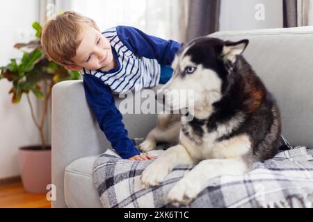 Garçon et chien Husky sur le canapé Banque D'Images