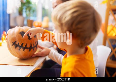 Enfant pointant le visage de la citrouille peinte Banque D'Images