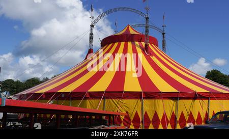 Bridgend, pays de Galles - 7 juillet 2024 : un grand cirque aux couleurs vives, en jaune et rouge. Les cordes de guidage ou de haubanage augmentent la stabilité structurelle o Banque D'Images