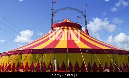 Bridgend, pays de Galles - 7 juillet 2024 : un grand cirque aux couleurs vives, en jaune et rouge. Les cordes de guidage ou de haubanage augmentent la stabilité structurelle o Banque D'Images