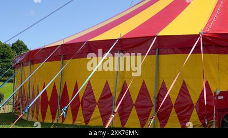 Bridgend, pays de Galles - 7 juillet 2024 : un grand cirque aux couleurs vives, en jaune et rouge. Les cordes de guidage ou de haubanage augmentent la stabilité structurelle o Banque D'Images