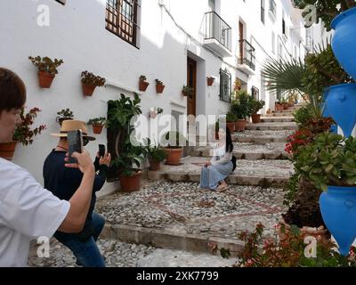 Touristes prenant des photos les uns des autres posant dans la pittoresque rue de village étroite Instagrammable, Frigiliana, Andalousie, Espagne Banque D'Images