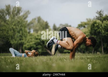 Les personnes qui font de l'exercice à l'extérieur dans un parc, y compris un homme qui fait du yoga et une femme qui fait des sit-ups Banque D'Images
