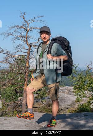 Un homme d'âge moyen avec un sac à dos sur le dos profite du paysage montagneux. Vallée de l'Elbe, parc national de la Suisse saxonne, Allemagne. Banque D'Images