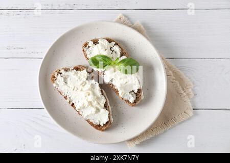 Bruschettas avec ricotta et basilic sur table en bois blanc, vue de dessus Banque D'Images