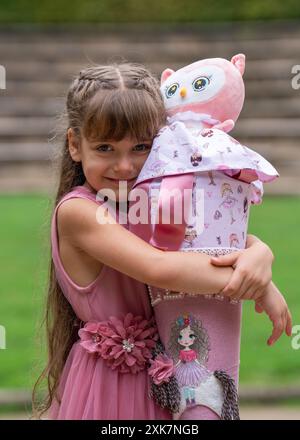 Heureuse petite fille serrant son cône d'école dans la rue. Banque D'Images