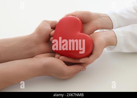 Docteur et patient tenant le coeur rouge sur fond blanc, gros plan Banque D'Images