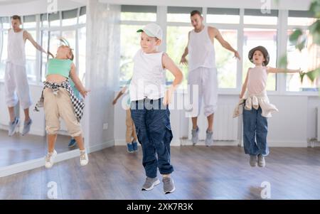 Tween Boy Jumping avec des pairs et instructeur au cours de danse de groupe Banque D'Images