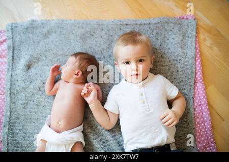 Portrait de mignon petit bébé allongé sur le lit à côté de son frère aîné. Banque D'Images