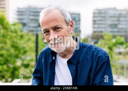 Heureux homme senior souriant à la caméra debout sur fond urbain Banque D'Images