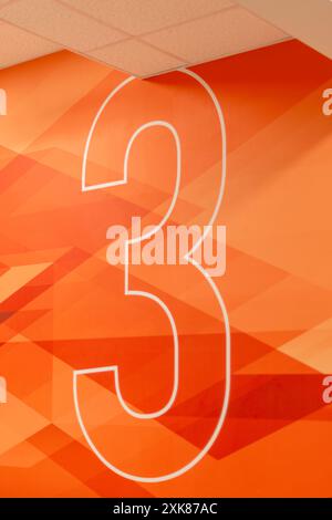 Le numéro trois est en texte blanc sur fond orange vif et rouge. L'indicateur de niveau de sol a plusieurs formes géométriques faites à partir de différentes teintes Banque D'Images