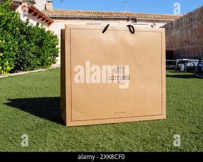 Palma, Espagne - 11 juillet 2024 : un sac en papier de chaussures de luxe Lotusse 1877 Mallorca est placé dans un jardin luxueux dans une finca à Majorque, soulignant l'élégance et le style haut de gamme Banque D'Images