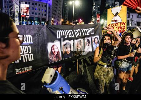 Tel Aviv, Israël. 20 juillet 2024. Les manifestants se rassemblent et chantent autour d'une banderole avec les photos des soldats israéliens Liri Elbag, Karina Ariev, Agam Berger, Daniela Gilboa et Naama Levi - prises en otage par le Hamas le 7 octobre depuis la base militaire de Nahal Oz pendant la manifestation. Plus de 100 000 Israéliens ont manifesté à Kaplan avec les familles des otages contre le premier ministre Benjamin Netanyahu, exigeant un accord immédiat sur les otages et un cessez-le-feu - un jour avant le départ de Netanyahu pour parler devant le congrès américain à Washington. Crédit : SOPA images Limited/Alamy Live News Banque D'Images