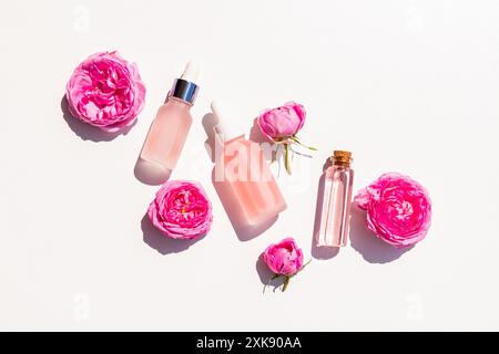 produits cosmétiques en différentes bouteilles à base d'huile de rose pour les soins de la peau du visage et du corps. Soin spa. aromathérapie. Pose à plat. vue de dessus. fond blanc. Banque D'Images