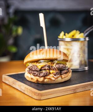 Hamburger de bœuf double debout sur une ardoise noire, gros plan Banque D'Images
