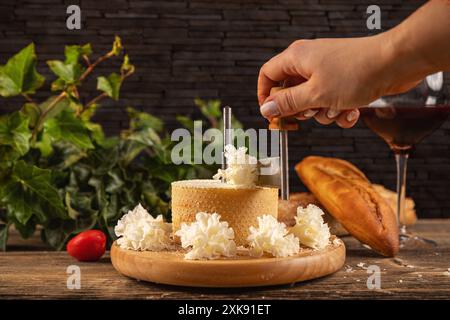 Femme tranchant de délicieux fromages sur une planche de bois Banque D'Images