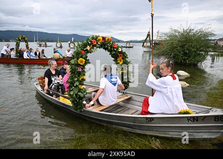 Radolfzell am Bodensee, Allemagne. 22 juillet 2024. Tradition catholique sur le lac de Constance : des dizaines de croyants font un pèlerinage de Moos sur des bateaux décorés à travers le lac de Constance jusqu'à Radolfzell, où ils atterrissent sur le rivage. Ils remplissent un vœu fait en 1797, lorsque le bétail des agriculteurs Moos a été épargné par une épidémie. La procession a été créée en remerciements. Des centaines de personnes accueillent les pèlerins sur la rive de Raldolfzell sur le lac de Constance. Crédit : Felix Kästle/dpa/Alamy Live News Banque D'Images