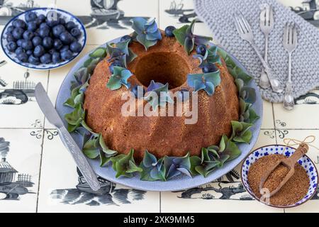 gâteau gugelhupf avec farine complète sur une assiette décorée de fleurs d'hortensia et de bleuets Banque D'Images