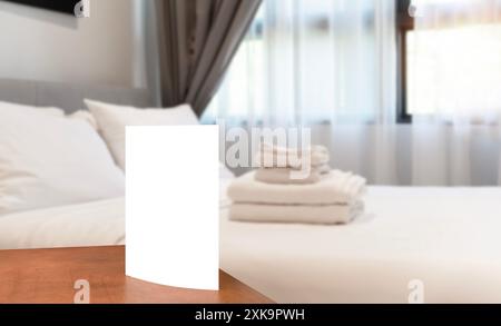 Panneau blanc carton avec espace de copie sur une table ronde blanche. Intérieur de l'hôtel. Carte blanche vide sur un porte-carte dans une chambre d'hôtel Banque D'Images
