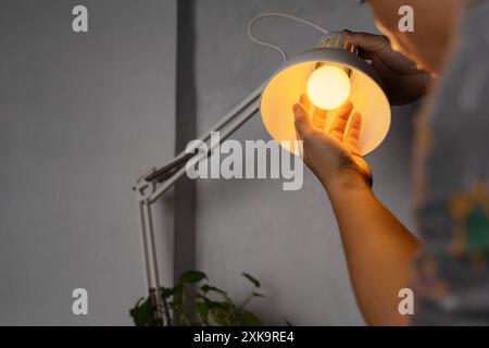 Changement d'ampoule LED électrique dans la lumière à la maison. Bricoleur choisissant entre économie d'énergie et lampe à incandescence bon marché tout en changeant la lumière dans l'appartme Banque D'Images