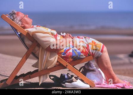 Une femme âgée endormie et relaxante dans un transat, Skegness, Lincolnshire, Royaume-Uni Banque D'Images