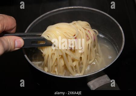 Tagliatelles étant cuites maison et bouillies dans une poêle sur une plaque de cuisson Banque D'Images