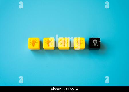 Une ampoule éteinte parmi les autres ampoules incandescentes. Le concept d'épuisement et d'épuisement créatif. Faites une pause. Maintenir un équilibre entre les deux Banque D'Images