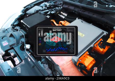 Technicien de voiture vérifie l'état de santé de SOH de la batterie avec des outils de scanner sans fil pour voiture électrique, concept de réparation de voiture électrique Banque D'Images