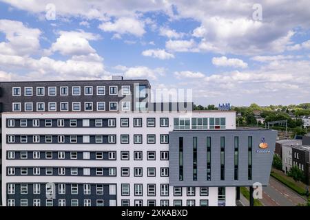 Les agriculteurs néerlandais de la banque Rabobank s'élevant au-dessus des maisons résidentielles au lever du soleil du ciel orange. Institution financière et siège social de l'immobilier d'entreprise Banque D'Images