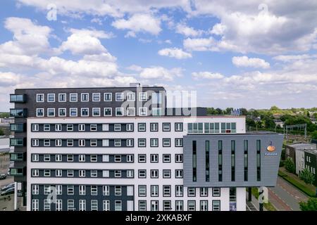 Les agriculteurs néerlandais de la banque Rabobank s'élevant au-dessus des maisons résidentielles au lever du soleil du ciel orange. Institution financière et siège social de l'immobilier d'entreprise Banque D'Images