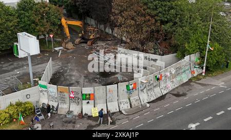 LES RÉDACTEURS NOTENT LE LANGAGE DE GRAFFITTI SUR LA BARRICADE vue générale des manifestants devant l'ancienne usine de peintures Crown à Coolock, au nord de Dublin, qui a subi plusieurs incendies criminels suite à des plans de réaménagement de l'entrepôt désaffecté pour héberger les demandeurs d'asile. Date de la photo : lundi 22 juillet 2024. Banque D'Images