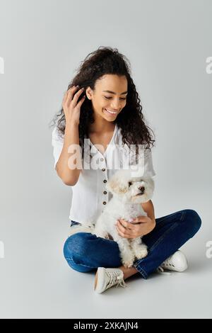 La femme s'assoit paisiblement avec son Bichon Frise blanc sur le sol. Banque D'Images