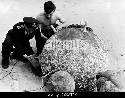 Les soldats allemands attachent un engin explosif à une mine marine échouée sur la plage. Photo non datée. [traduction automatique] Banque D'Images