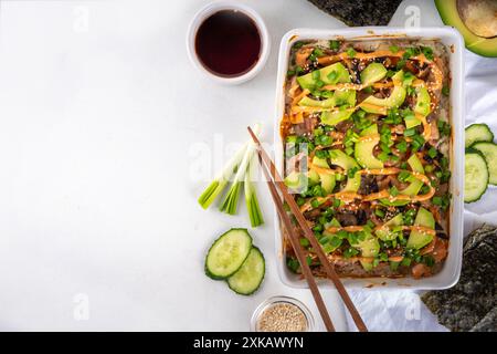 Philadelphia Sushi Bake recette casserole à base de riz, fromage à la crème, truite saumon, algues, avocat, sauce, oignon vert. Servi avec des feuilles de nori grillées Banque D'Images