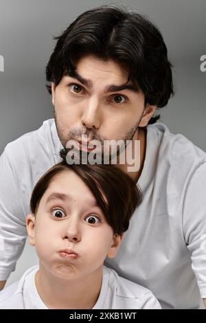 Un homme et un jeune garçon se faisant des visages drôles ensemble. Banque D'Images