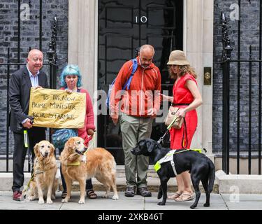 Londres, 22 juillet 2024. (g-t-R) Steve Darling, Sarah Gayton, bénévole et pétitionnaire. La National Federation of the Blind of the UK (NFBUK) remet une pétition au 10 Downing Street appelant à un arrêt temporaire de tous les arrêts de bus flottants prévus dans les nouvelles voies cyclables à travers le Royaume-Uni, car il s'agit d'une préoccupation importante pour la sécurité des personnes aveugles et autres. La pétition est organisée par Sarah Gayton (aux cheveux bleus), soutenue par le président de l'Association européenne des chiens aveugles, David Adams avec le chien Jimbo et le député de Libdem Steve Darling avec le chien guide Jennie, Sarah Leadbetter avec Nellie, et d'autres. Banque D'Images