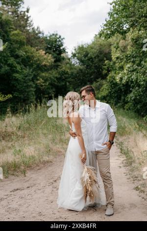 jeunes couples de jeunes mariés sur une promenade dans une forêt de pins Banque D'Images