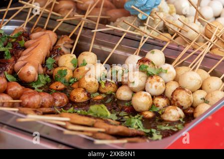 Cuisine de rue thaïlandaise, saucisses ainsi que boulettes de viande et de poisson sur bâtonnets. Banque D'Images