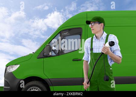 Un homme en uniforme tient la fiche de charge du véhicule électrique. Fourgonnettes électriques en arrière-plan. Banque D'Images