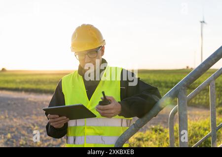 Ingénieur avec tablette numérique contrôle les éoliennes. Banque D'Images