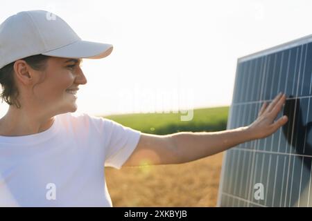 Femme touche un panneau solaire au coucher du soleil. Banque D'Images