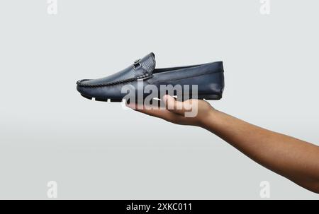 : mocassins en cuir glisse sur des chaussures tenant en main sur fond clair Banque D'Images