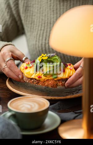 Une femme portant un toast à l'avocat et au houmous dans un restaurant. Heure du brunch. Banque D'Images