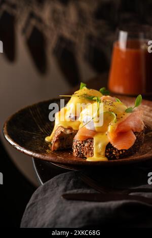 Tranches de pain avec du saumon et des œufs de hollandaise sur le dessus. Table de restaurant. Pain grillé au levain. Banque D'Images