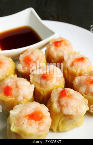 Gros plan de boulettes chinoises cuites à la vapeur fourrées de crevettes et de porc appelées Shumai sur une assiette blanche Banque D'Images