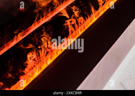 Une vue rapprochée de flammes réalistes dans une cheminée électrique moderne, ajoutant chaleur et ambiance à la pièce. Banque D'Images