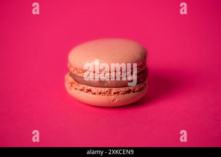 Un macarons avec une garniture de noisette est montré dans une vue rapprochée. Le macaron est isolé sur un fond blanc, qui met en valeur son colo rouge vif Banque D'Images