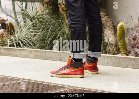 Homme, mec en jeans bleu foncé et bottes marron en cuir debout sur le chemin dans le jardin botanique de cactus, serre. Un explorateur de la nature. jambes, pieds mis au point. Banque D'Images